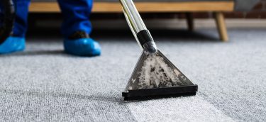 Janitor Cleaning Carpet With Vacuum Cleaner At Home