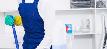 Young female cleaner in protective uniform polishing surfaces at company office